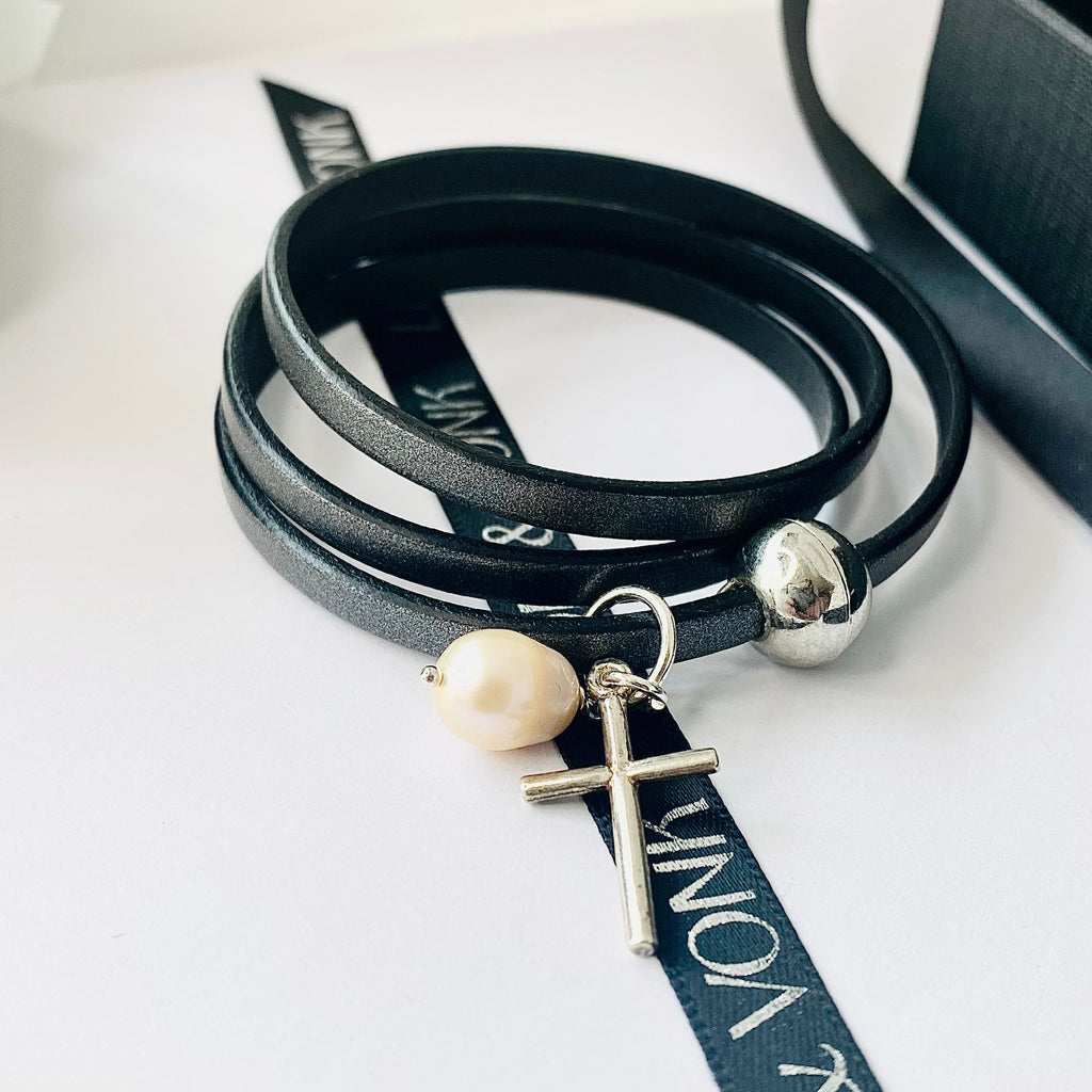 Leoni & Vonk grey leather bracelet with silver cross and pearl charm on a white background with Leoni & Vonk ribbon