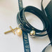 Leoni & Vonk grey leather bracelet with silver cross and pearl charm on a white background with Leoni & Vonk ribbon