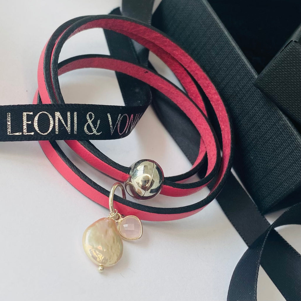 Leoni & Vonk pink leather bracelet with pearl ahd heart charm on a white background and with Leoni & Vonk ribbon.