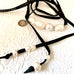 Leoni & Vonk leather and pearl necklace on a white textured background and with Leoni & Vonk ribbon