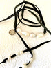 Leoni & Vonk leather and pearl necklace on a white textured background and with Leoni & Vonk ribbon