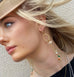Blonde model wearing Leoni & Vonk long statement earrings and a straw hat. She is looking out to the side of the image