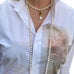 Upper torso of a woman wearing a white shirt and Leoni & Vonk long pearl necklace