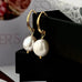 Leoni & Vonk gold and white pearl earrings on a black box and with Leoni & Vonk ribbon