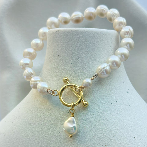 Leoni & Vonk pearl bracelet with a gold fob clasp hanging on a white vase