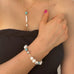 Cropped image of a girl wearing Leoni  & Vonk pearl and howlite jewellery. Her arm is across her body.