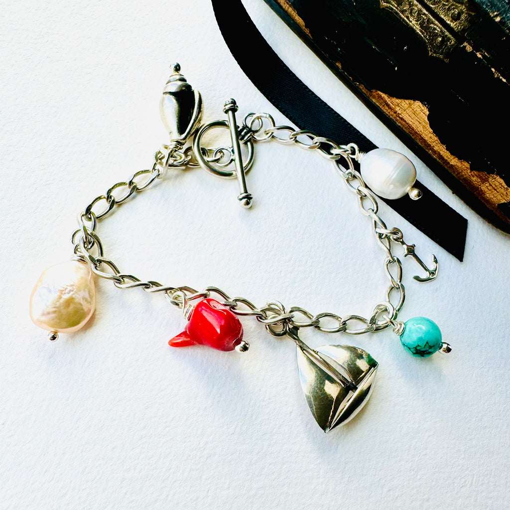 Leoni & Vonk sterling silver charm bracelet with sailboat, shell, anchor, pearl and semi precious stone charms on  awhite background