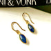 Leoni & Vonk sapphire and gold drop earrings on a white background with Leoni & Vonk ribbon