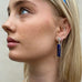 Blonde model wearing leoni & Vonk silver and sapphire September birthstone earrings. She is looking out to the left of the image.