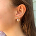 Cropped image of a dark haired girl wearing Leoni & Vonk pearl star and moon earrings