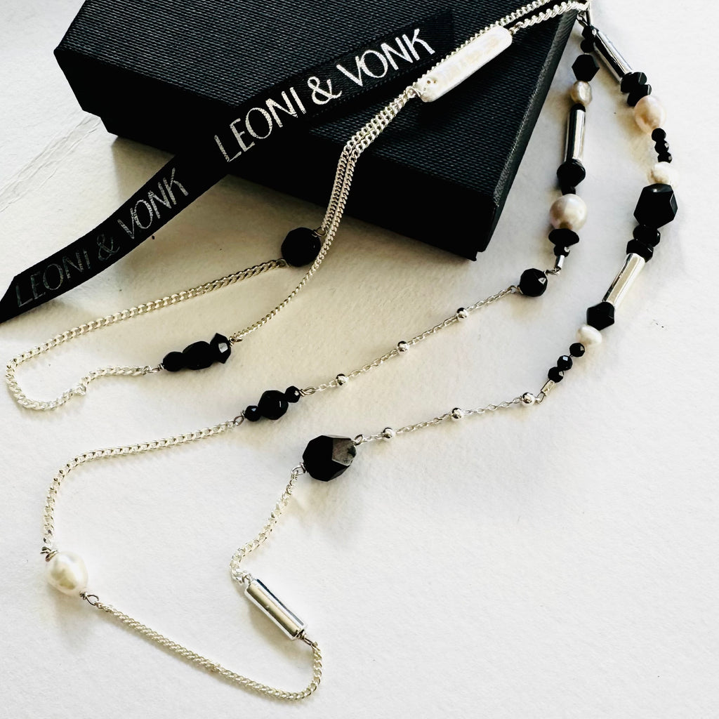 Leoni & Vonk packaging featuring a black box, Leoni & Vonk ribbon and a pearl necklace. The inside of the lid has writing saying "created with a whole lot of love"