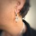 Cropped image of a woman wearing Leoni & Vonk silver charm earrings.