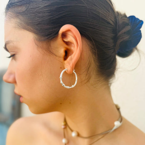 Dark haired girl looking to the right of the image. She is wearing Leoni & Vonk silver hoop earrings and has her hair up.