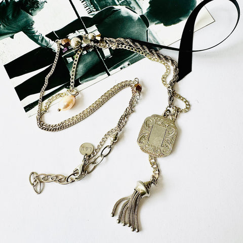 Leoni & Vonk Stokes and Victorian tassel necklace on a white background with a vintage postcard.