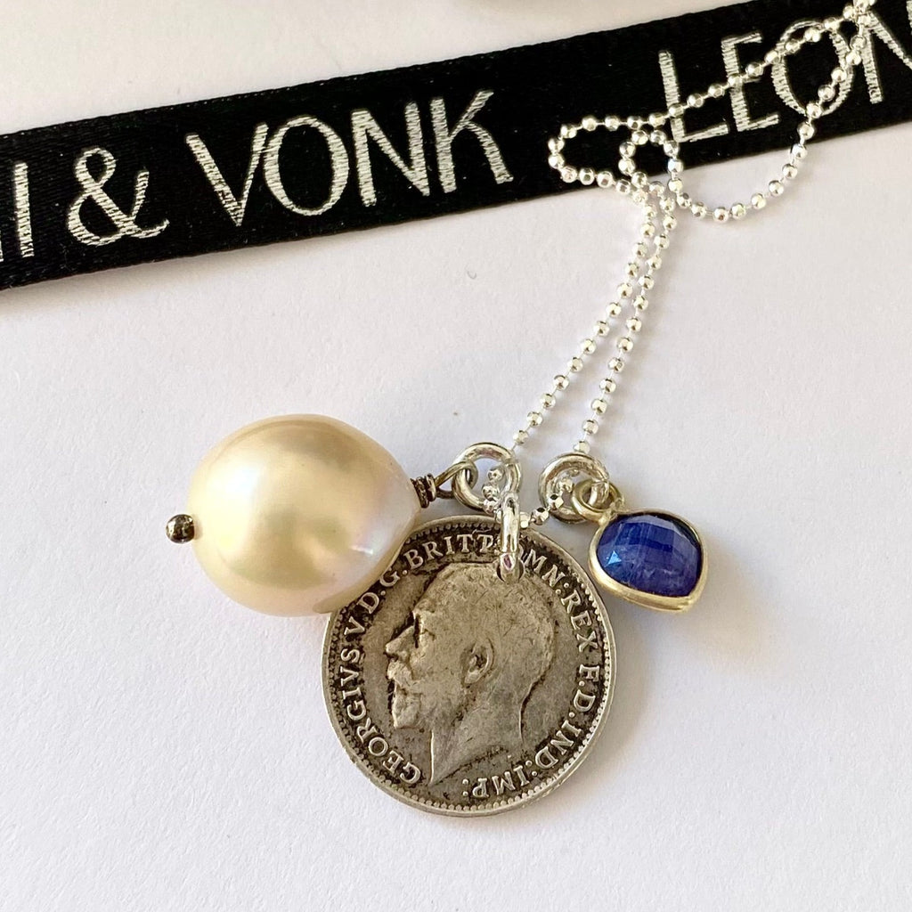 Leoni & Vonk antique 1918 British threepence with a sapphire heart and baroque pearl drop on a sterling silver chain. The necklace is on a white background with Leoni & Vonk ribbon