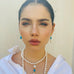 Dark haired girl wearing Leoni & Vonk pearl and turquoise jewellery and looking straight out at the camera