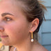 Image of a girl looking to the left of the image wearing Leoni & Vonk gold pearl drop earrings