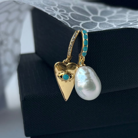 Leoni & Vonk pearl and gold heart earrings on a black box with white flower ribbon