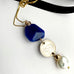 Leoni & Vonk lapis, 1917 British Indian coin and keshi pearl on a gold chain and on a white background with some black ribbon