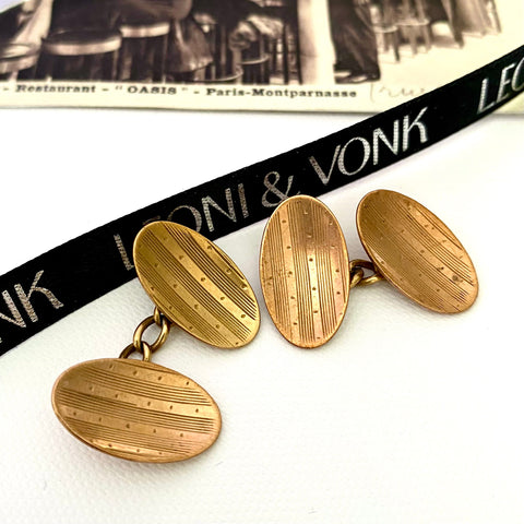Leoni & Vonk gilt antique cufflinks made by John Atkins and sons and photographed near Leoni & Vonk ribbon and a vintage postcard
