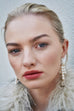 Model wearing Leoni & Vonk statement pearl earrings and a white Zara fluffy jacket