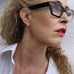 Blonde woman wearing glasses looking to the side of the frame. She  is wearing leoni & Vonk jewellery and a white shirt