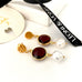 Leoni & Vonk garnet, gold and white keshi pearl stud earrings photographed near a white box and Leoni & Vonk ribbon