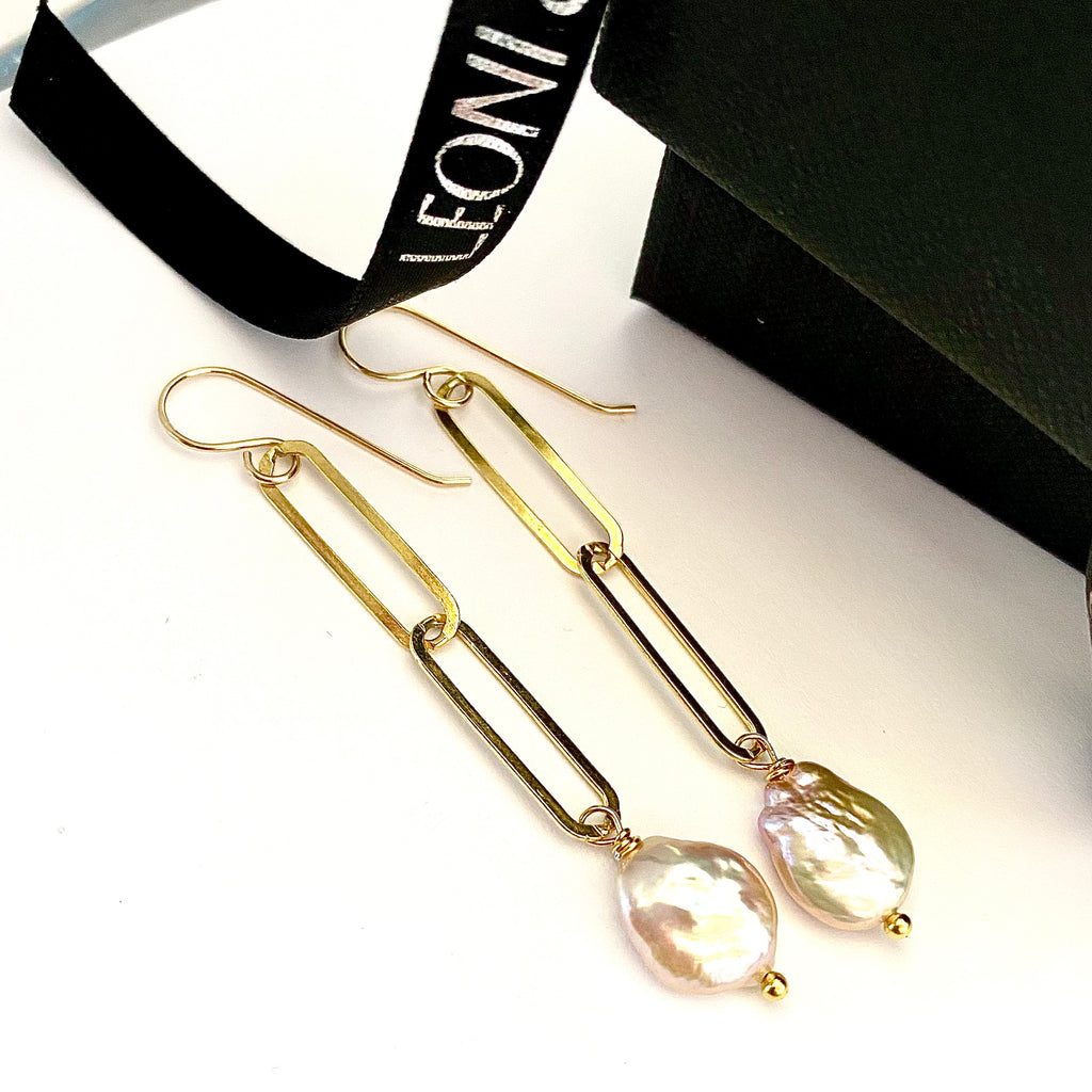 Leoni & Vonk gold paperclip chain earrings with a pink keshi pearl drop . The earrings are on a white background with Leoni 7 Vonk ribbon and a black box in the background.