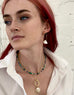 Redhaired model wearing Leoni & Vonk jewellery and a white shirt staring out to the side of the camera.