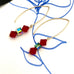 Leoni & Vonk And Greeves St red swarovski crystal earrings on a line drawing and with black ribbon