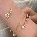 Leoni & Vonk gold and pearl bracelets and personalised E bracelet on a girls wrist