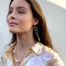 Dark haired woman wearing a sequin shirt and Leoni & Vonk jewellery looking upwards.