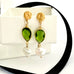 Leoni & Vonk August birthstone peridot and pearl earrings with a gold stud on a white box and with black ribbon