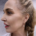 Blonde woman looking to the left of the image. She has her hair in a plait and is wearing Leoni & Vonk pearl earrings.