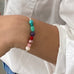 IMage of a womans wrist wearing a Leoni & Vonk brightly coloured gemstone bracelet and a white shirt.