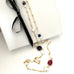 Leoni & Vonk ruby, sapphire, pearl gold necklace photogrpahed near a white box and ribbon