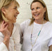 IMage of 2 women talking and laughing. They are both wearing Leoni & Vonk jewellery and white shirts/T shirts