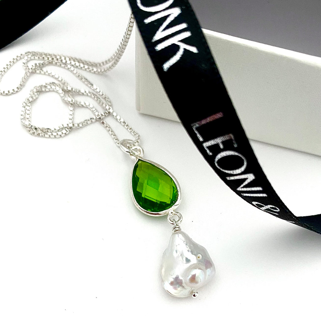 Leoni & Vonk peridot and pearl August birthstone necklace photographed near Leoni & Vonk ribbon and a white box