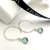 Leoni & Vonk aquamarine sterling silver dot hoop earrings photographed near a white box and Leoni & Vonk ribbon