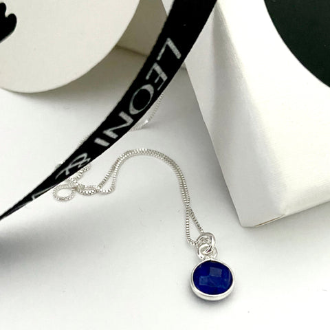 Leoni & Vonk sapphire and sterling silver necklace on a sterling silver chain photographed near a white box and leoni & Vonk ribbon