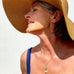 Grey haired woman wearing a big sun hat and Leoni & Vonk turquoise jewellery. She has her eys closed and her head is lifted to the side of the image.