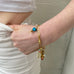 Image of a woman's hand holding onto her jeans. She is wearing a Leoni & Vonk venetian bead charm bracelet.