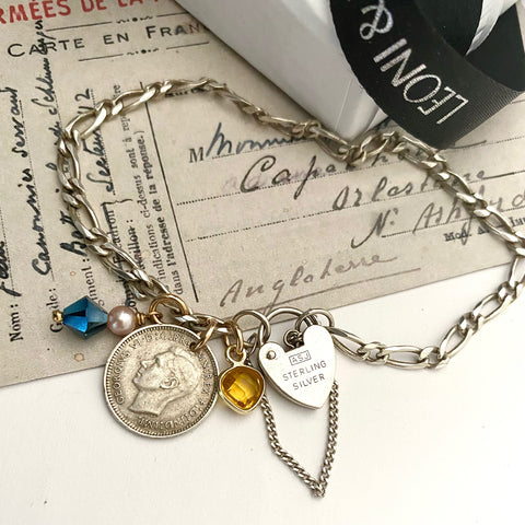Leoni & Vonk sterling silver vintage bracelet with 1944 Australian threepence and charms on a vintage postcard