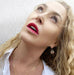 Blonde curly haired woman looking up and is wearing Leoni & vonk jewellery
